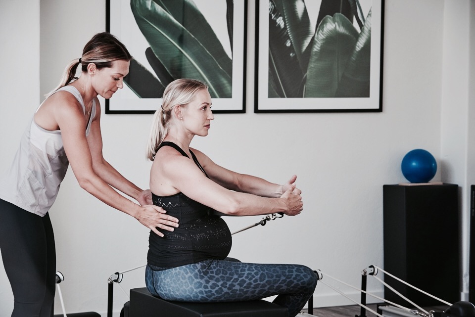 instructor assisting pregnant student with pregnant yoga