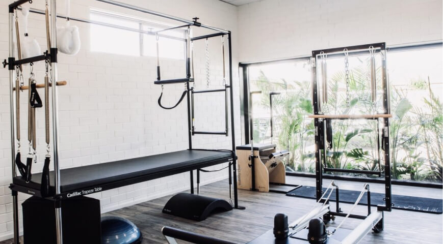 instructor assisting student in private pilates class